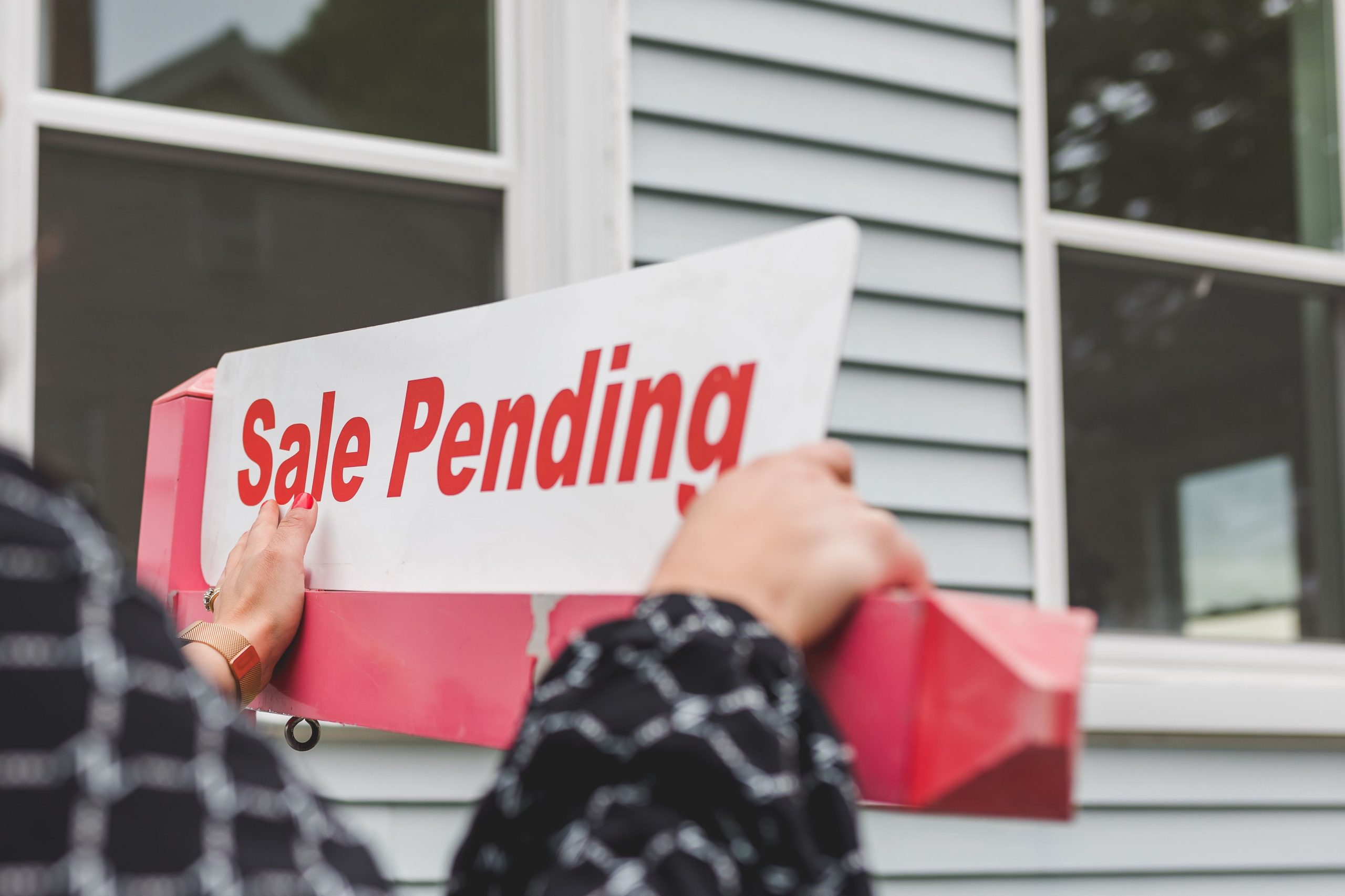 Mains pancarte vente immobilière devant maison