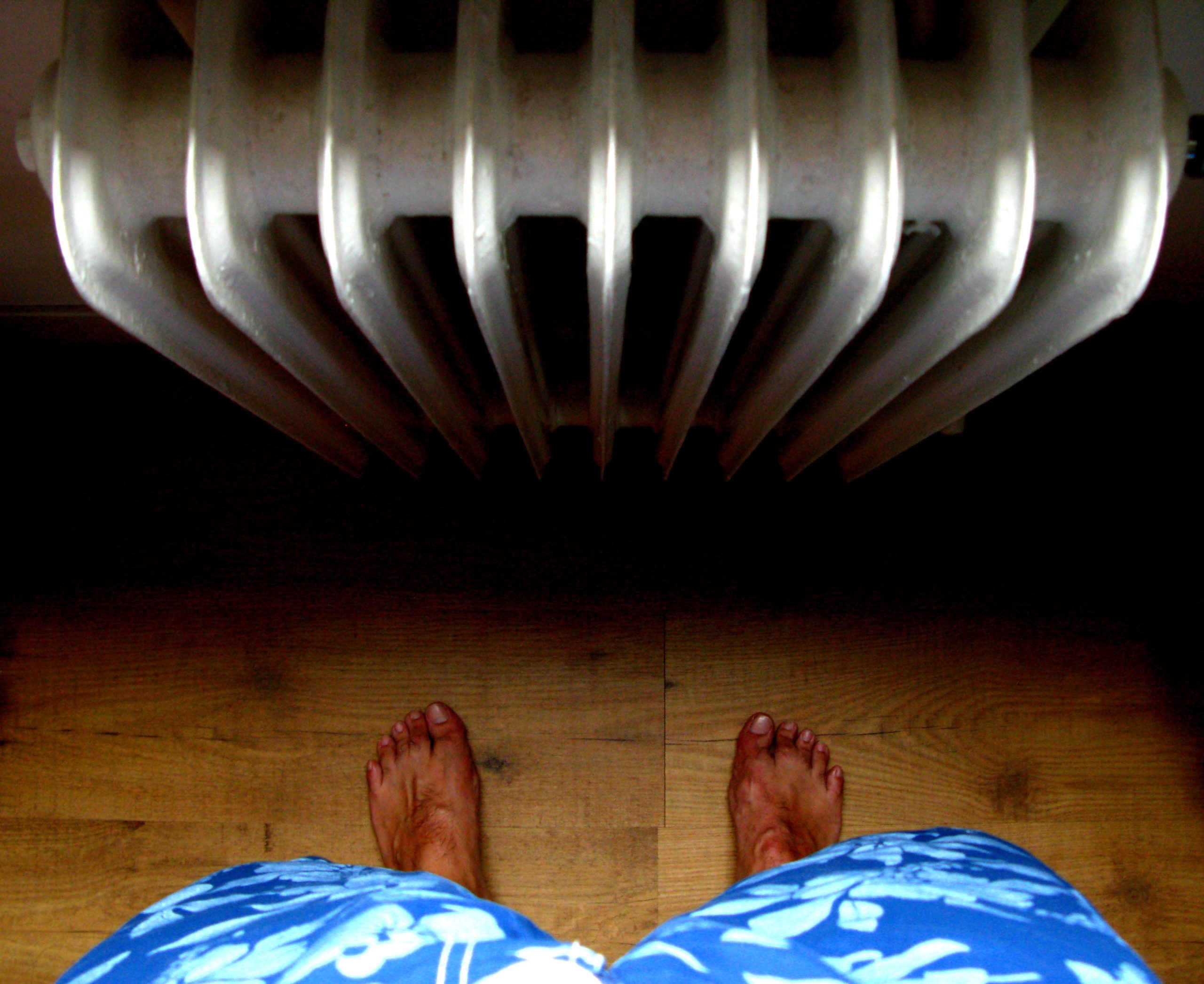 Pieds nus près d'un radiateur en bois