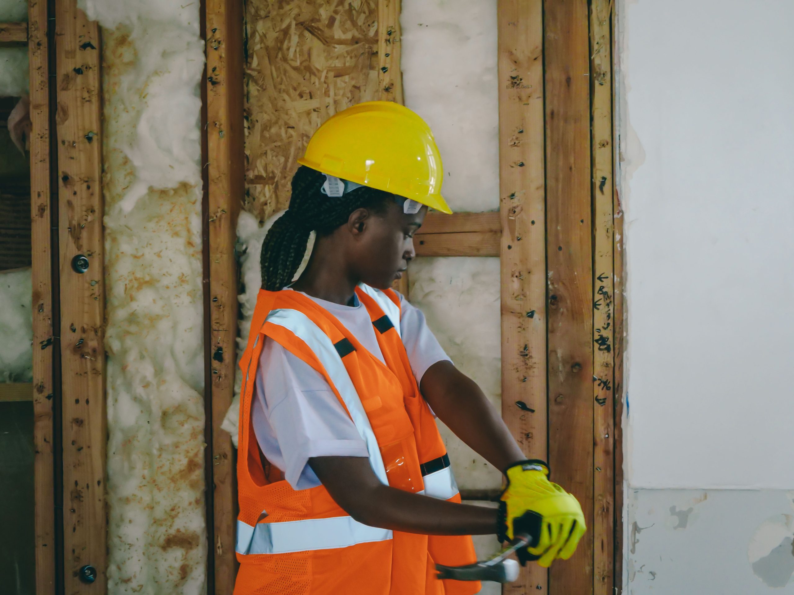 Femme ouvrier en équipement frappant sur chantier